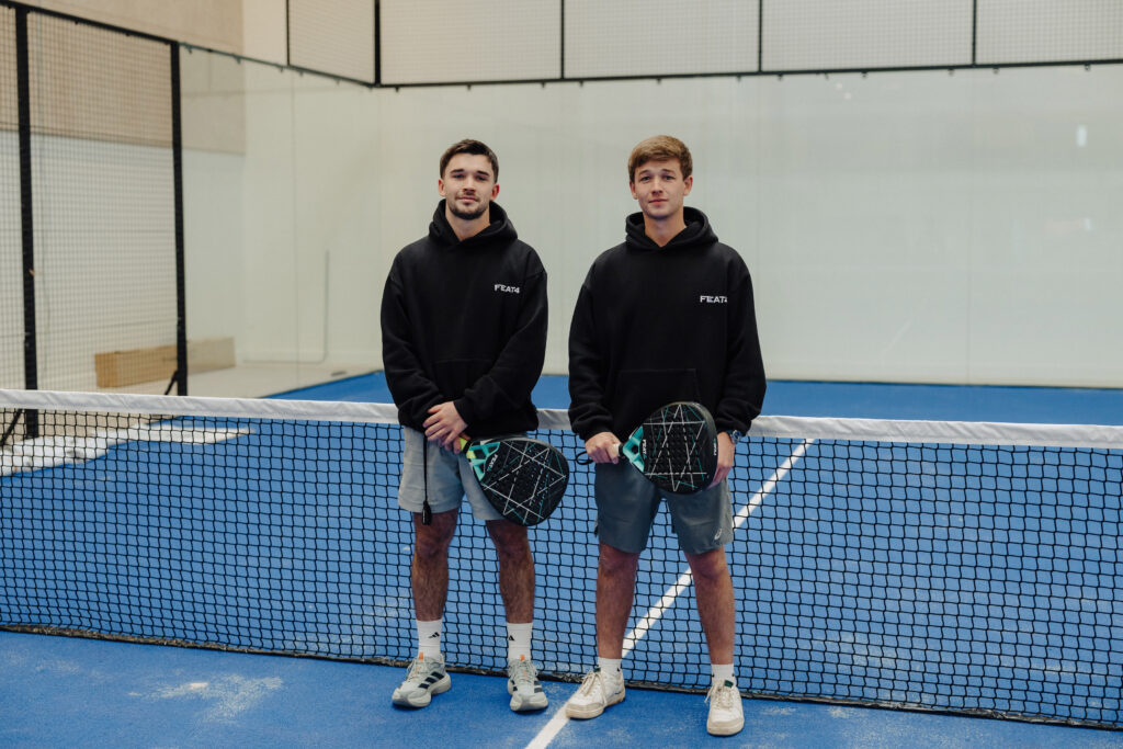 FEAT4 co-founders Charlie and Edward Conroy standing on a padel court with rackets